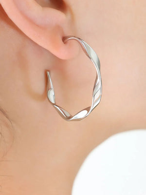 Silver sculpted twist hoop earrings with a modern, chic design.