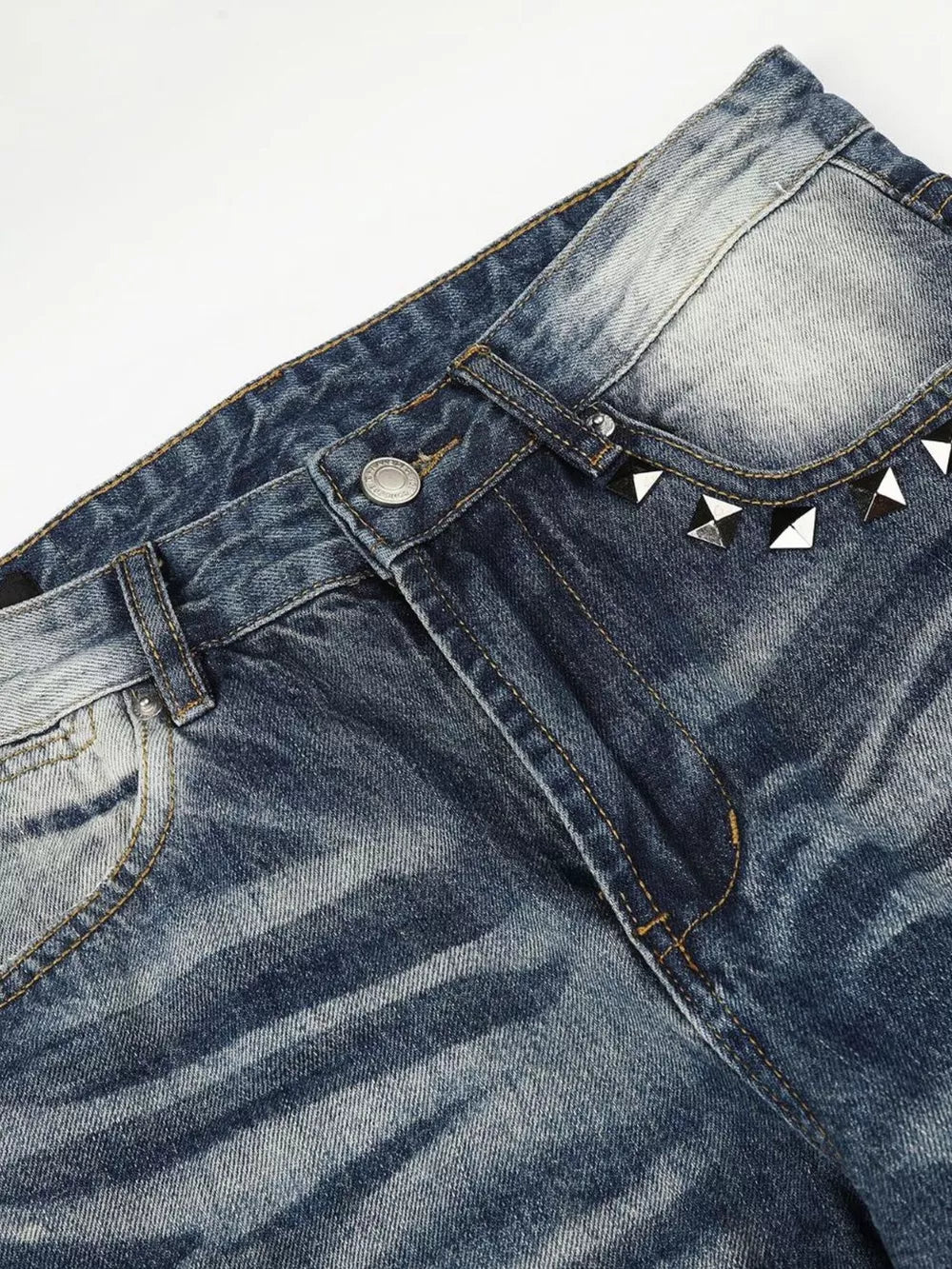 Blue distressed bootcut jeans with studded accents on the waistband.