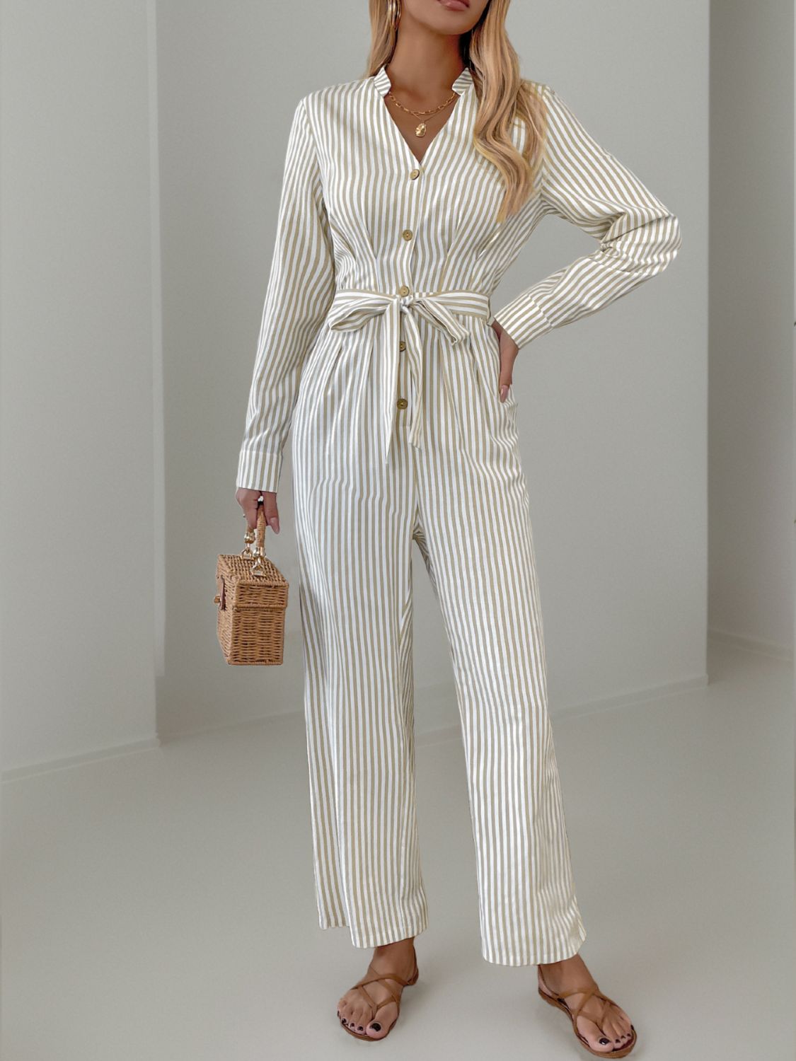 Beige vertical stripe button-down jumpsuit with a tie waist and long sleeves.