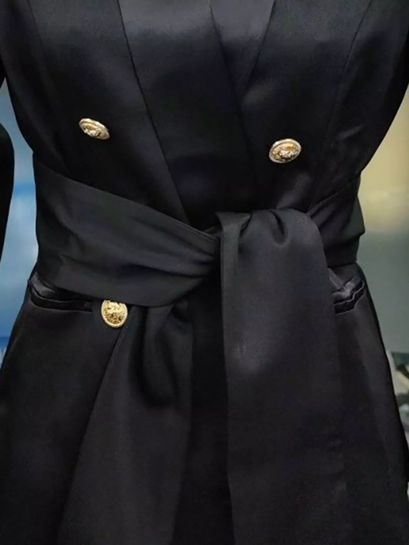 Black double-breasted blazer with gold buttons and a satin sash tie waist.
