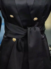 Black double-breasted blazer with gold buttons and a satin sash tie waist.