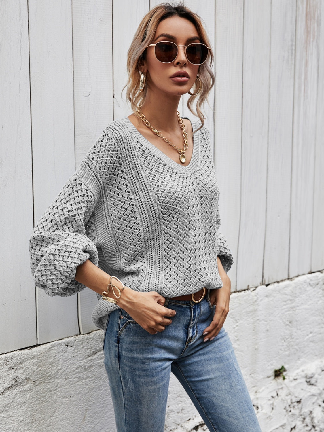 Light gray open-knit sweater with balloon sleeves and a V-neck, styled with jeans.