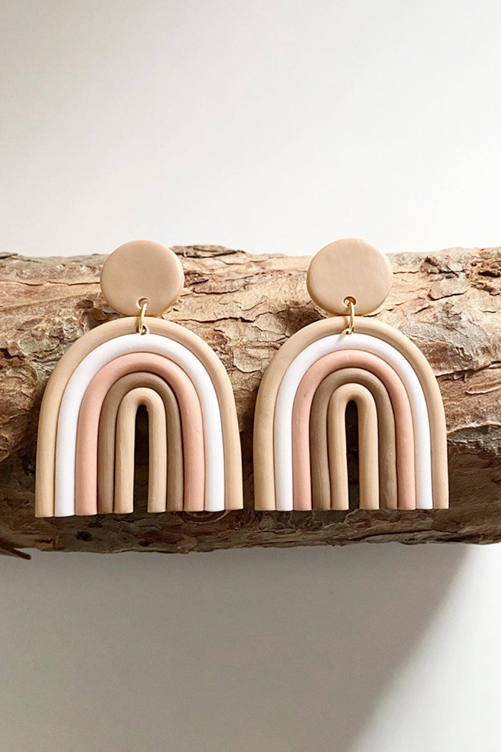 Clay rainbow arch earrings in tan, pink, white, and ivory with tan circle tops.