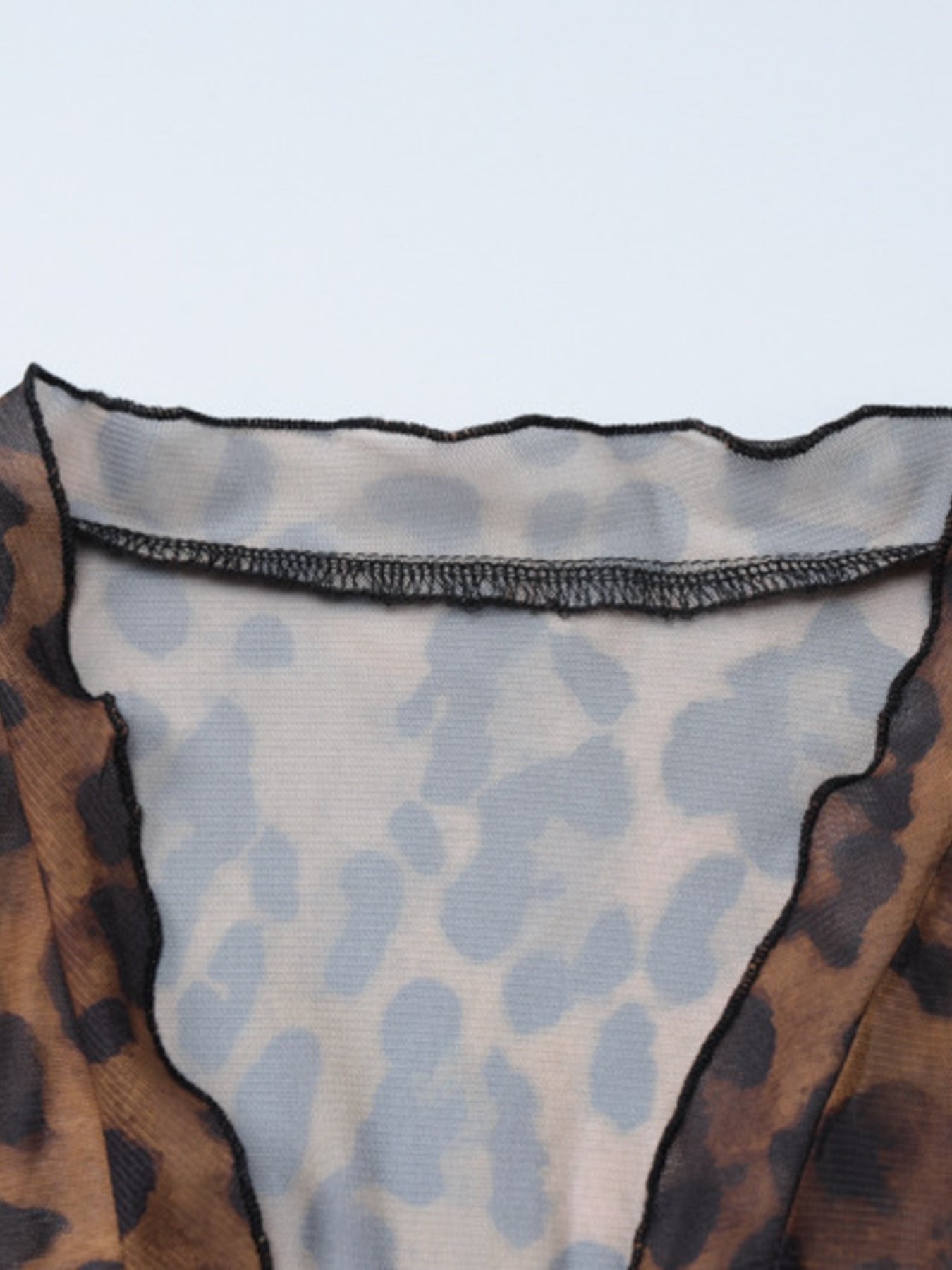 Sheer animal print mesh blouse with lettuce edge neckline and black stitching detail.