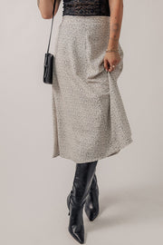 Dotted bias-cut midi skirt in heather gray, styled with black boots and a crossbody bag.