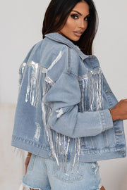 Denim trucker jacket in medium wash with distressed details and silver sequin fringe accents.