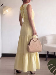 Yellow maxi dress with tiered skirt and tie-back detail.