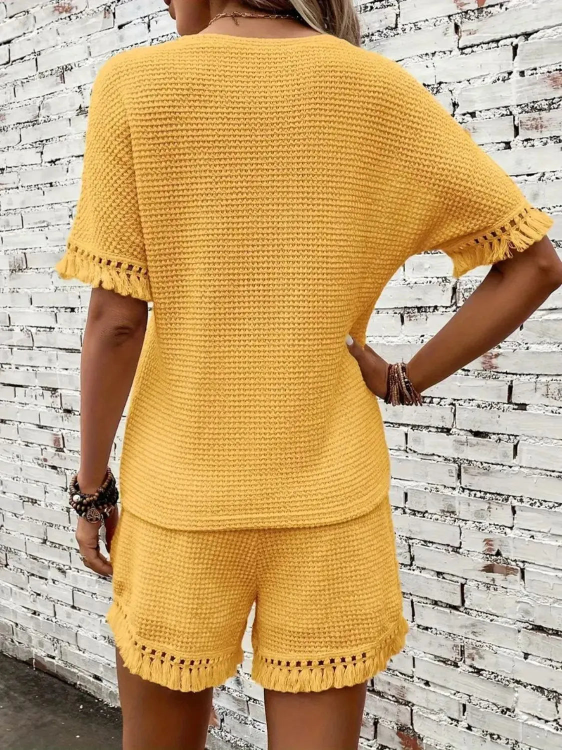 Textured knit set in gold with fringe trim on short sleeves and hem.