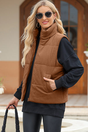Brown corduroy padded funnel neck vest with zipper and pockets, worn over a black sweatshirt.