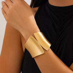 Sculptural gold-toned cuff bracelet with a modern, open design.