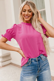 Hot pink blouse with ruffled neckline and smocked sleeves.