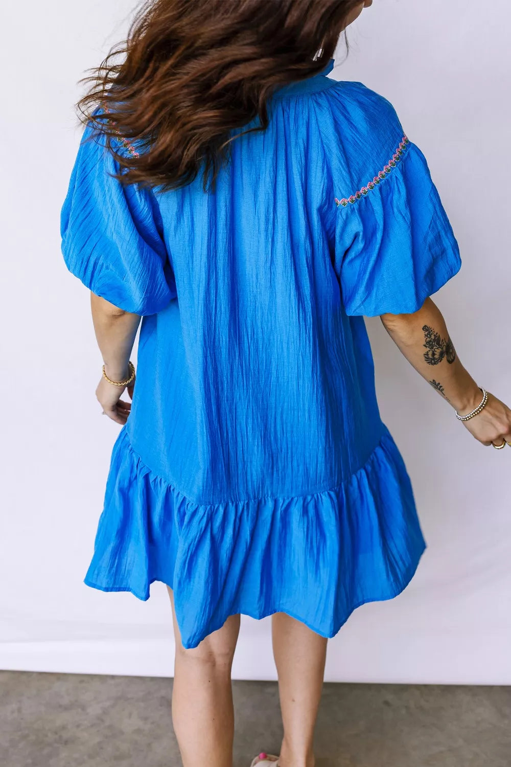 Blue embroidered floral ruffle hem dress with puff sleeves and textured fabric.