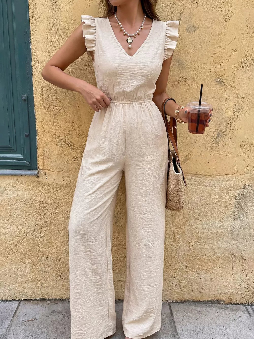 Cream ruffled V-neck wide-leg romper with elastic waist and textured fabric.