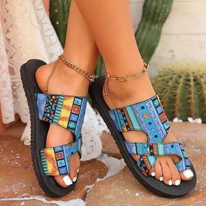 Geometric patterned toe loop sandals in blue with colorful accents and gold anklets.