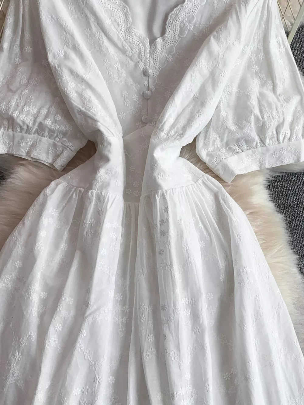 White lace-embellished A-line midi dress with button front and embroidered floral details.