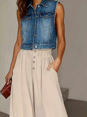 Beige wide-leg pants with paperbag waist and button front, styled with a denim vest.