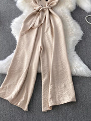 Apricot V-neck wide leg jumpsuit with tie belt and button detail.