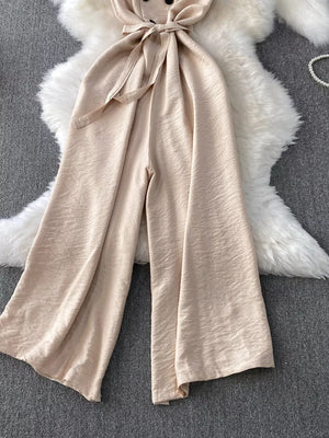 Apricot V-neck wide leg jumpsuit with tie belt and button detail.