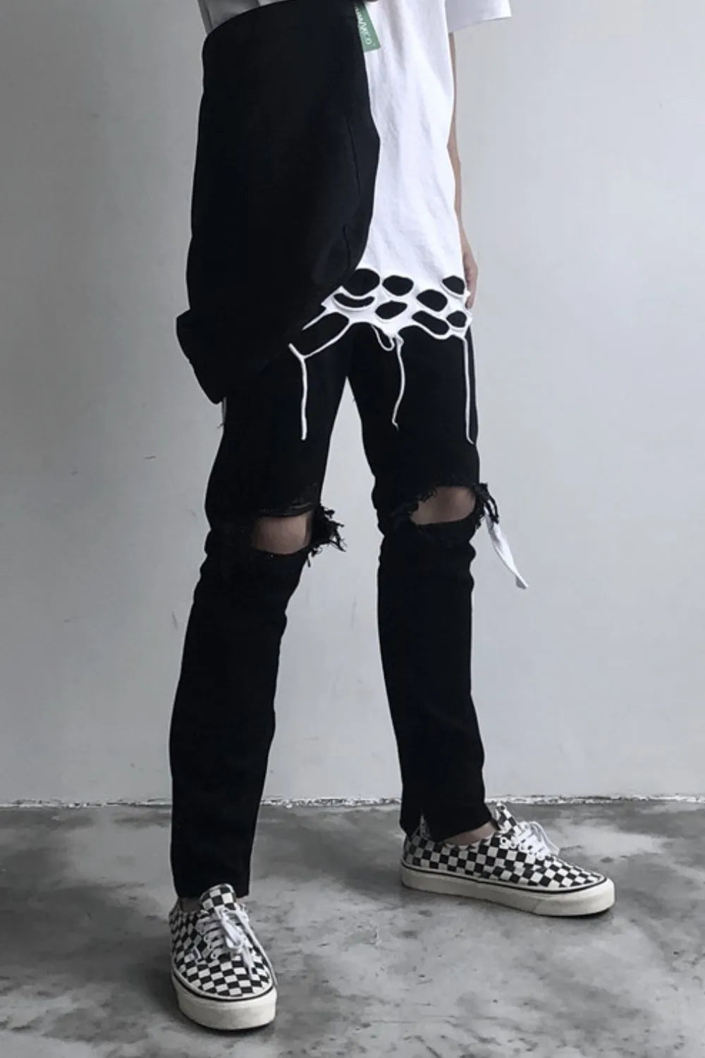 Black skinny fit jeans with distressed knees and frayed hem details.