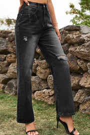 Distressed dark wide-leg denim trousers with ripped details and a button closure.