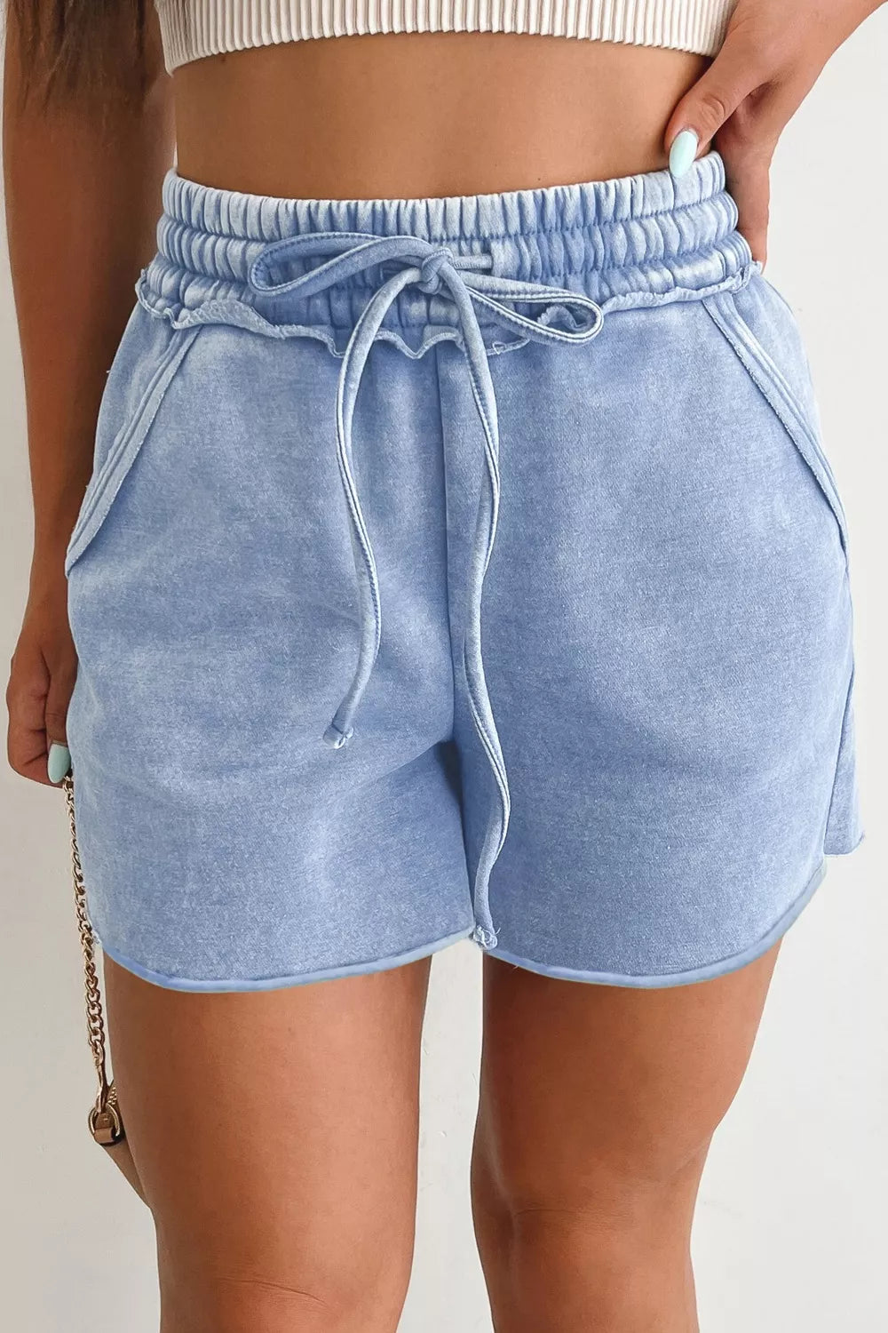 Light blue acid-washed drawstring shorts with pockets and a frayed hem.