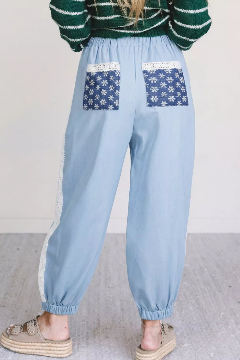 Light blue maternity pants with wide legs, lace trim, and snowflake-print back pockets.