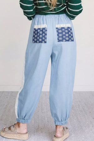 Light blue maternity pants with wide legs, lace trim, and snowflake-print back pockets.