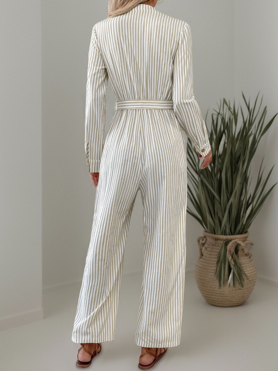 Beige vertical stripe button-down jumpsuit with belted waist and wide legs.