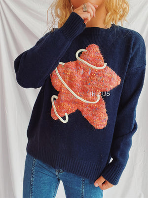 Navy knit jumper with embroidered orange starburst detail and white rope trim.