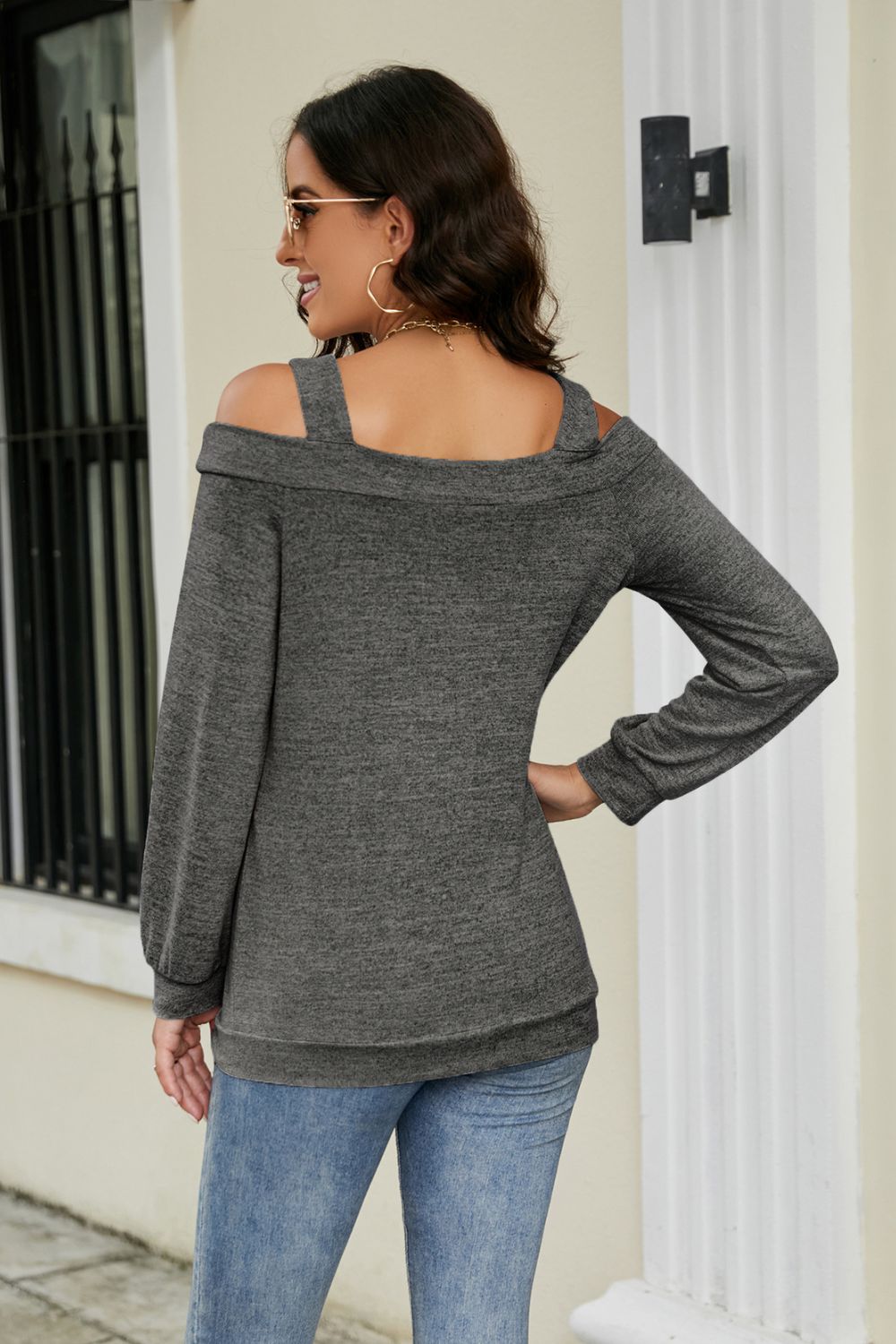 Gray sweater with cold shoulder cutouts and long sleeves, styled with jeans.