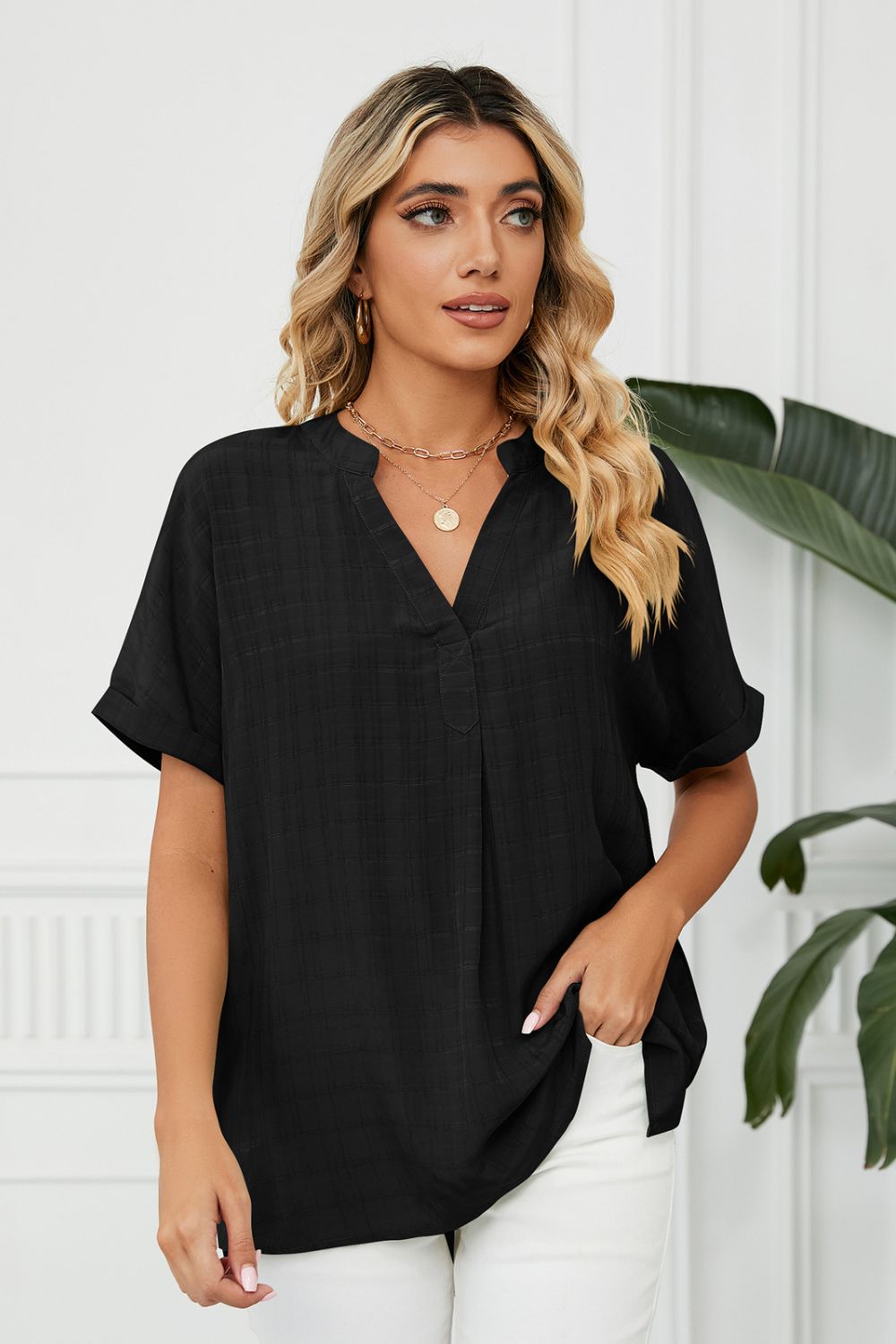 Black linen V-neck blouse with short sleeves and gathered back detail.