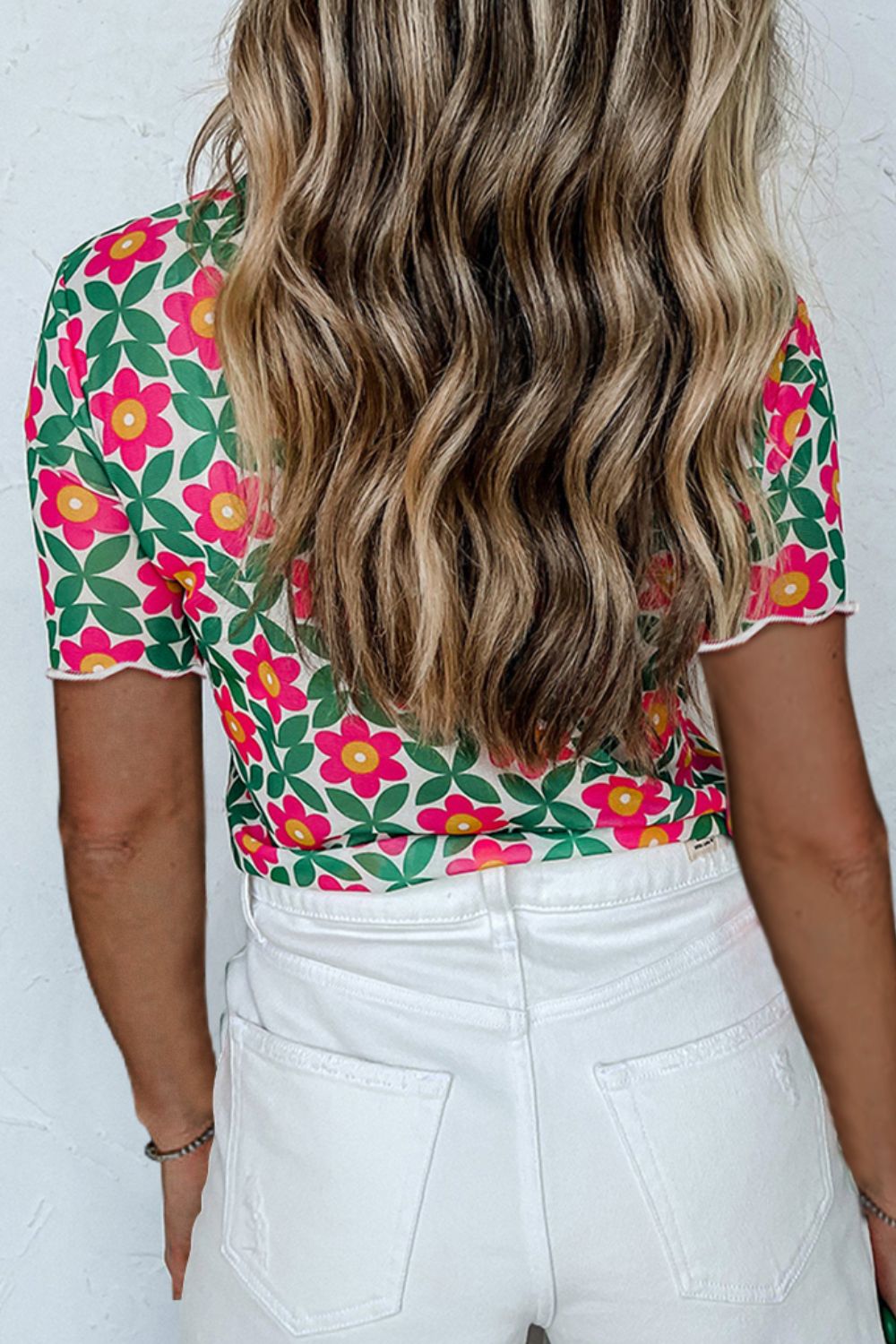 Floral tee with scallop trim and short sleeves, styled with white jeans.