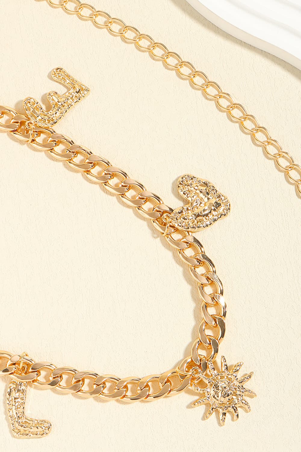 Gold chain belt with letter charms, heart and sun pendants.