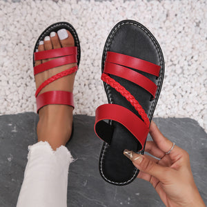 Red braided strap open-toe flat sandals with multiple straps and ankle strap detail.