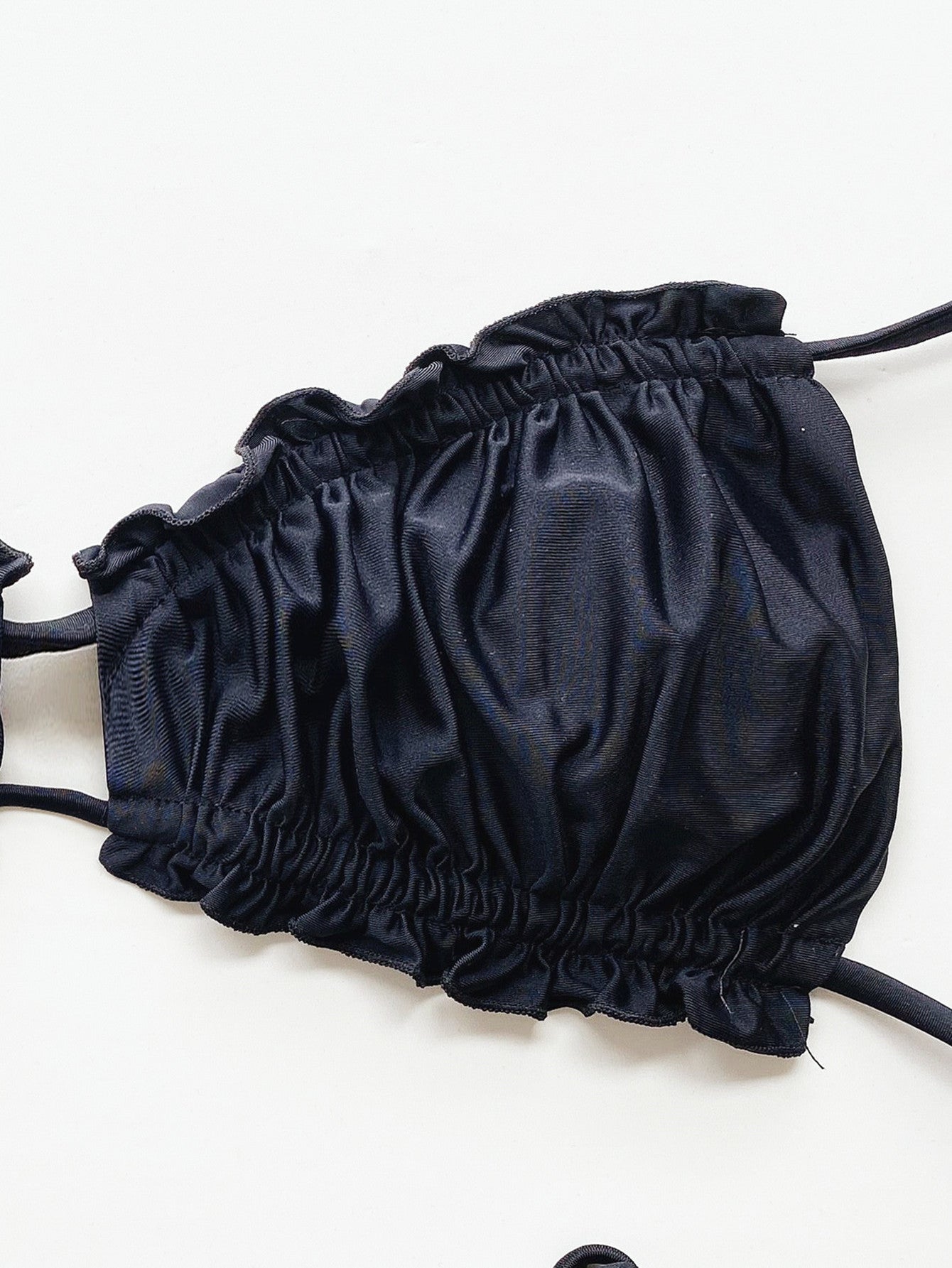 Black ruffle tie bikini top with ruched detail and tie straps.