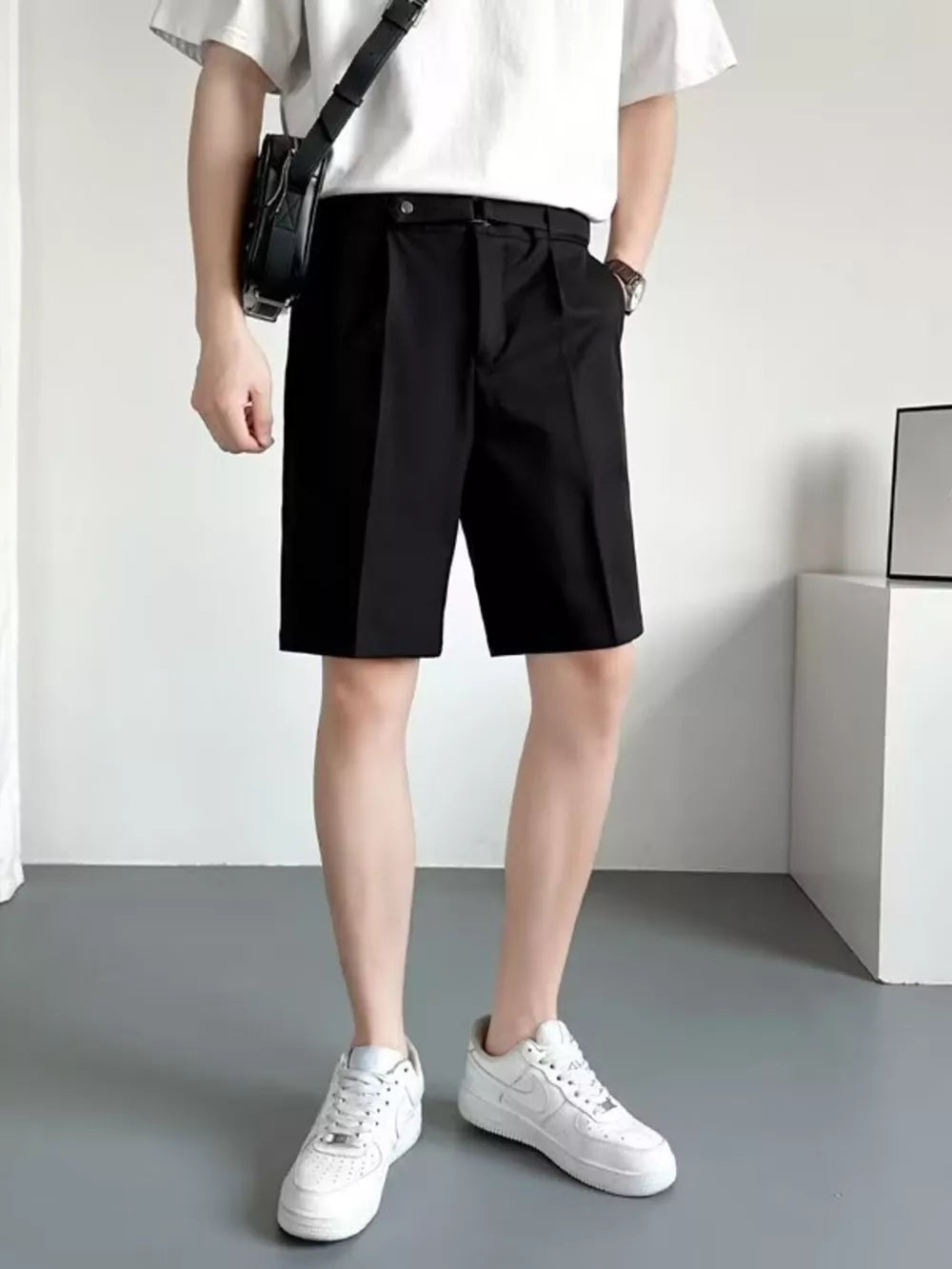 Men's black belted chino shorts with pleats and a relaxed fit.