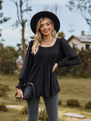 Black peplum blouse with gathered yoke and smocked cuffs, square neck, long sleeves.