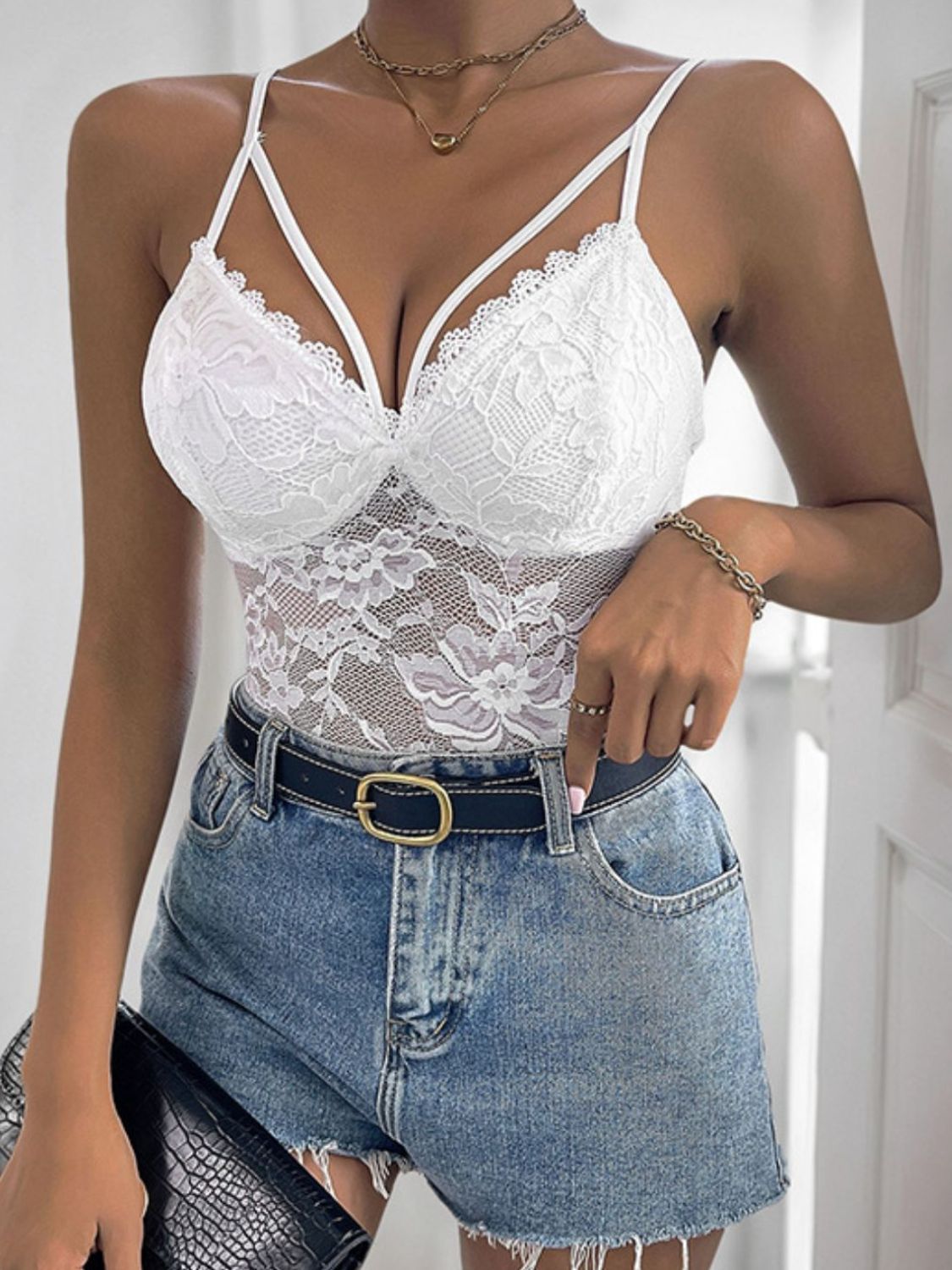 White floral lace crossover bodysuit with delicate straps and scalloped trim.