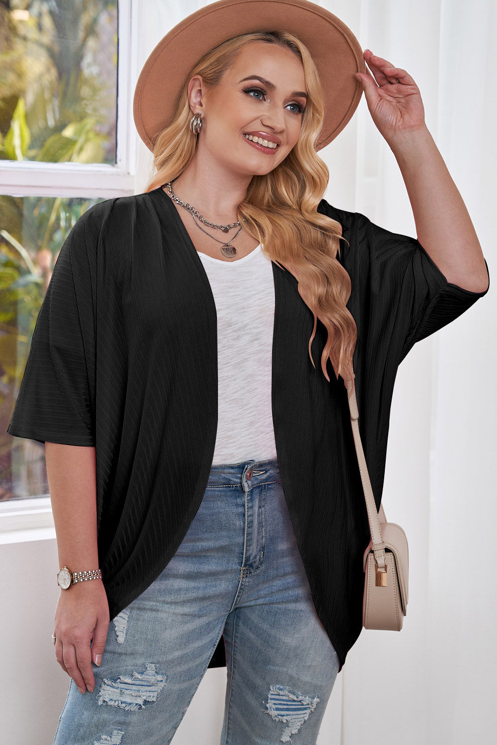 Black ribbed batwing cardigan with short sleeves and a drape front, worn over a white top.