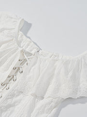 White eyelet lace-up corset tank top with ruffle trim and delicate floral embroidery.