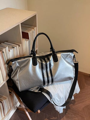 Sleek silver metallic duffle bag with black stripes and handles.