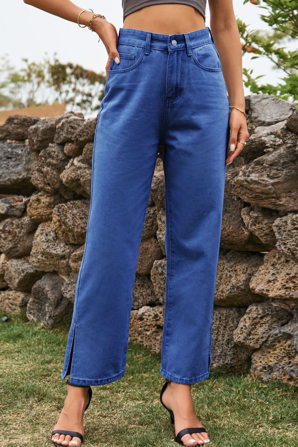 Medium wash denim straight leg jeans with cropped length and split hem detail.