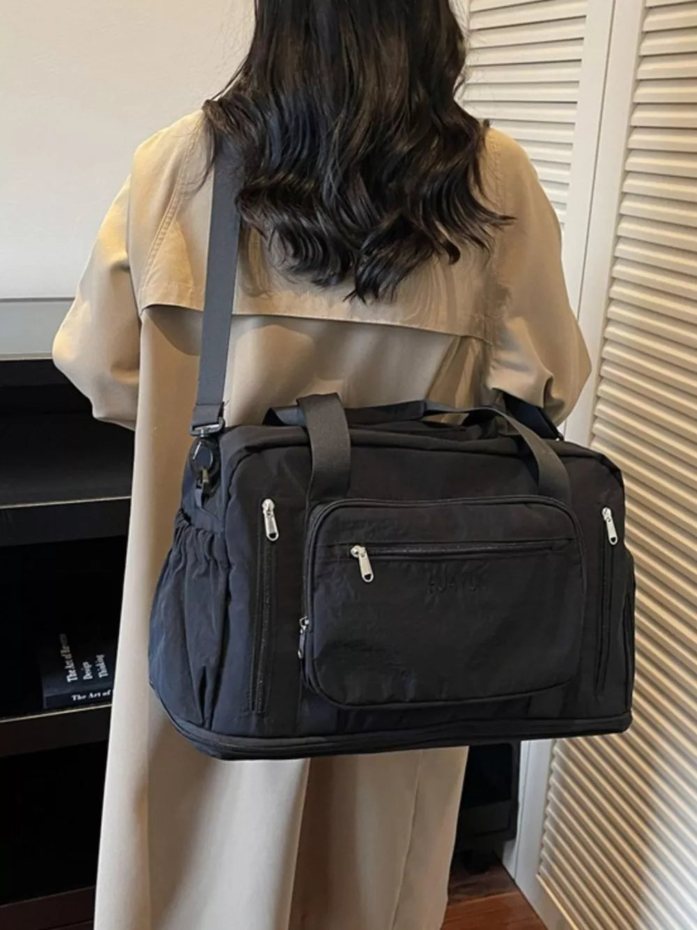 Black canvas duffel bag with multiple zippered pockets and adjustable strap.