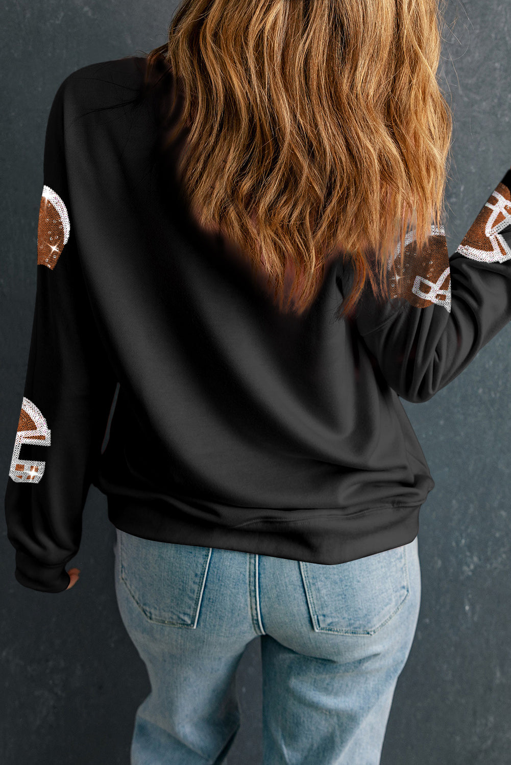 Black crewneck sweatshirt with sequin football helmet print on sleeves.