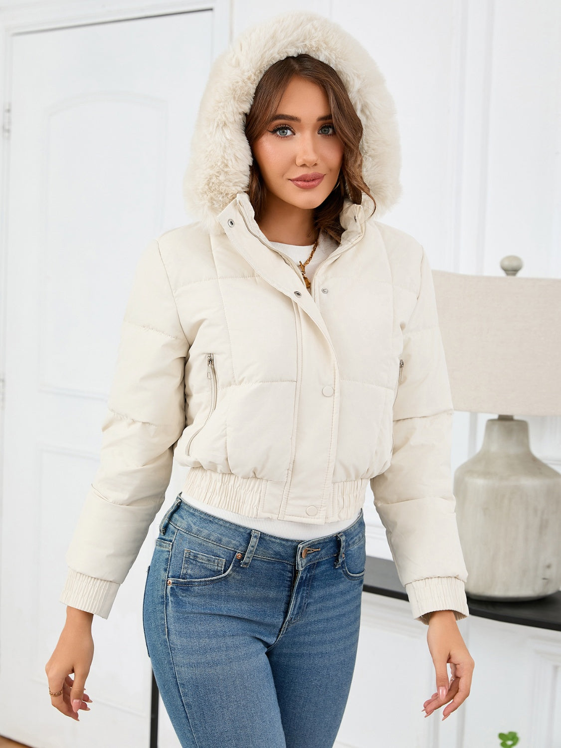 Cream puffer jacket with faux fur trim hood, cinched waist, and zip pockets.