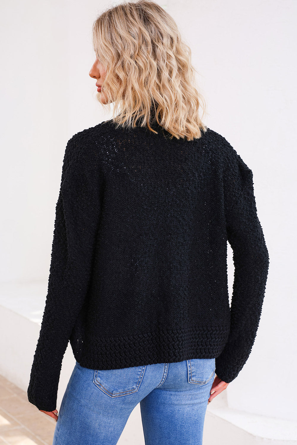 Textured black bouclé knit jacket with open front, long sleeves, and ribbed hem.