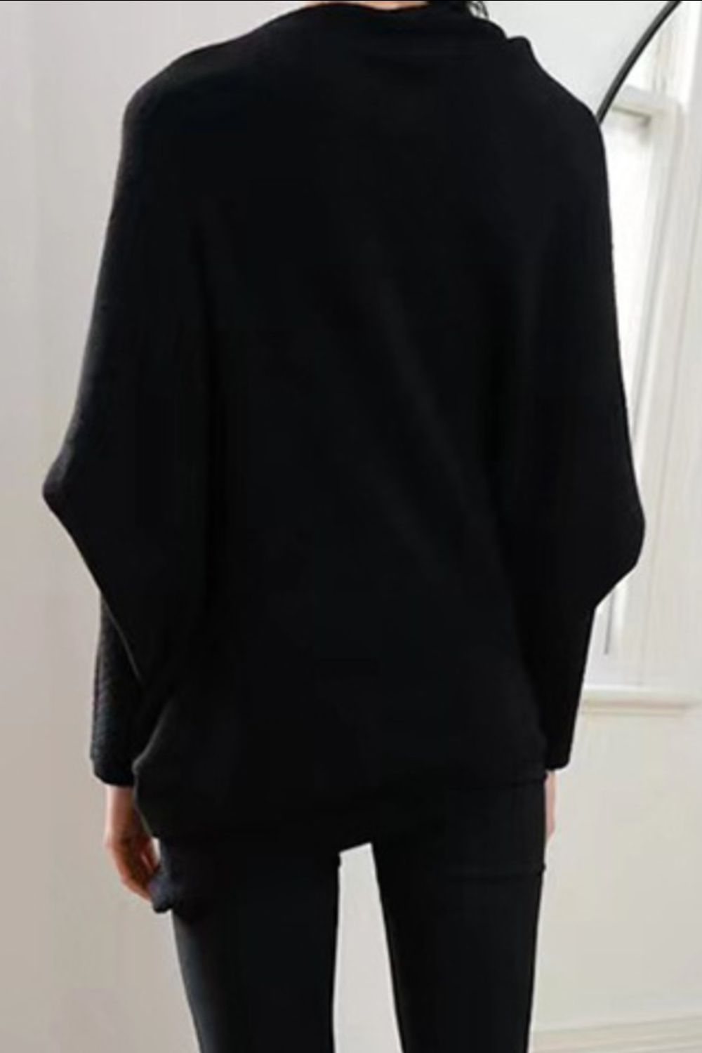 Black off-shoulder knit sweater with textured cuffs and batwing sleeves.