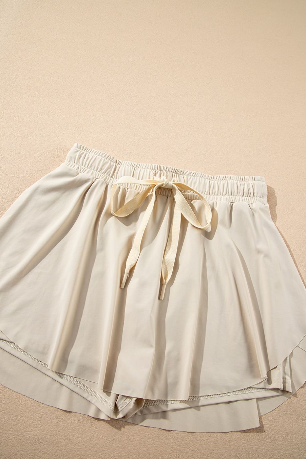 Beige ruffled skort with tie waist detail and elastic waistband.
