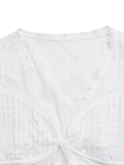 White lace-trimmed tie-front sleeveless maternity blouse with textured fabric and eyelet detail.