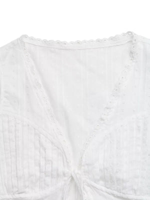 White lace-trimmed tie-front sleeveless maternity blouse with textured fabric and eyelet detail.